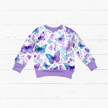 Laden Sie das Bild in den Galerie-Viewer, Baumwolljersey Schmetterlingswiese Pastell – Schmetterlinge in Türkis und Violett zwischen zarten Blüten auf hellem Grund. Kleidungs-Mockup: Flach ausgelegter Pullover.