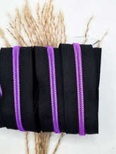 Laden Sie das Bild in den Galerie-Viewer, Endlosreißverschluss Schwarz Lila für #5-Zipper mit 6,5 mm Raupenbreite – Detailansicht, schwarzes Band mit lilafarbener Raupe.