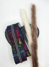 Laden Sie das Bild in den Galerie-Viewer, Endlosreißverschluss Chill mal für #5-Zipper, 6,5 mm Raupenbreite – schwarzes Band mit Rainbow-Raupe, dekorativ auf einem Herz mit Trockenblumen fotografiert.