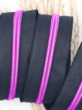 Laden Sie das Bild in den Galerie-Viewer, Endlosreißverschluss Schwarz Pink für #5-Zipper mit 6,5 mm Raupenbreite – Detailansicht, schwarzes Band mit pinkfarbener Raupe.