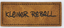 Laden Sie das Bild in den Galerie-Viewer, Detailaufnahme eines geprägten Kunstlederlabels „Kleiner Rebell“ für Hoodies, Jacken, Taschen und selbstgenähte Accessoires.