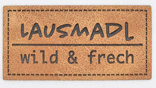 Laden Sie das Bild in den Galerie-Viewer, Detailaufnahme eines geprägten Kunstlederlabels „Lausmadl – wild & frech“ für Hoodies, Taschen und selbstgenähte Accessoires.