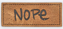 Laden Sie das Bild in den Galerie-Viewer, Detailaufnahme eines geprägten Kunstlederlabels „Nope“ im Format 5 × 2 cm für Hoodies, Taschen und selbstgenähte Accessoires.
