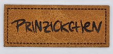 Laden Sie das Bild in den Galerie-Viewer, Detailaufnahme eines geprägten Kunstlederlabels „Prinzickchen“ für Hoodies, Taschen und selbstgenähte Accessoires.
