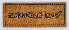 Laden Sie das Bild in den Galerie-Viewer, Detailaufnahme des geprägten Kunstlederlabels „Zornröschen“ in 5 × 2 cm für Hoodies, Taschen und selbstgenähte Accessoires.

